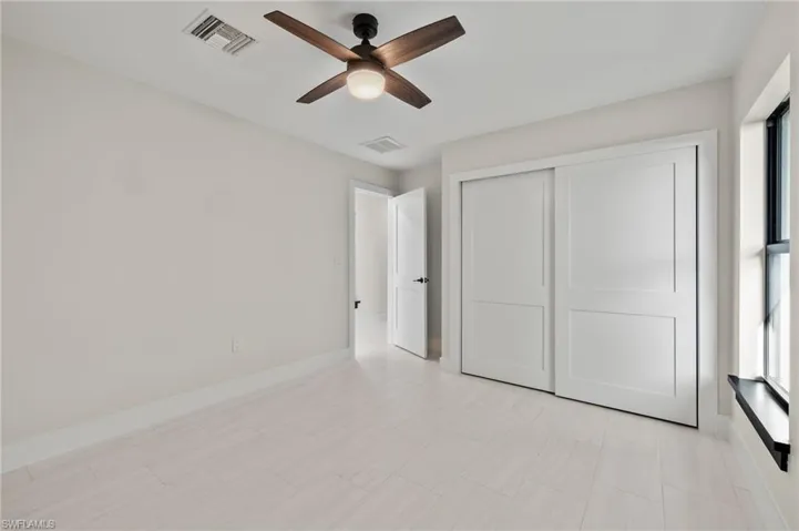 Unfurnished bedroom featuring a closet, light tile patterned floors, and ceiling fan