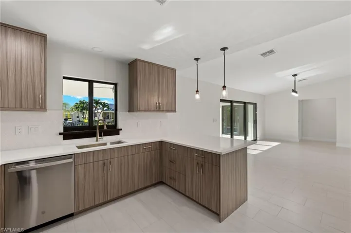 Kitchen featuring light tile patterned flooring, tasteful backsplash, kitchen peninsula, dishwasher, and pendant lighting