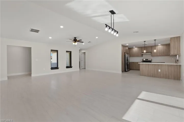 Unfurnished living room featuring sink, light tile patterned floors, and ceiling fan