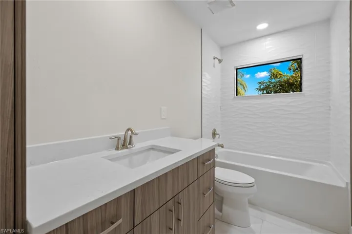 Full bathroom featuring tile patterned flooring, toilet, vanity, and tiled shower / bath