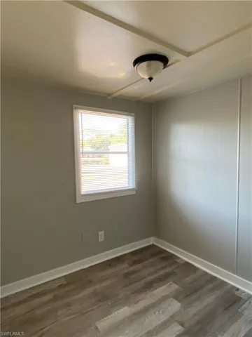 Unfurnished room featuring dark wood-type flooring and baseboards