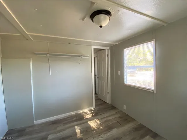 Unfurnished bedroom with dark wood-style floors and a closet