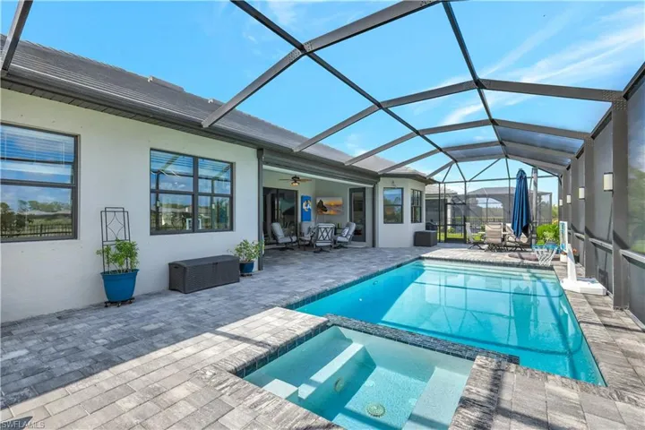 View of pool with a patio, a pool with connected hot tub, ceiling fan, and a lanai
