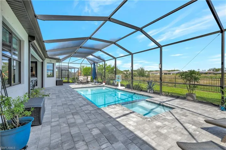 View of swimming pool with a patio area, a pool with connected hot tub, and glass enclosure