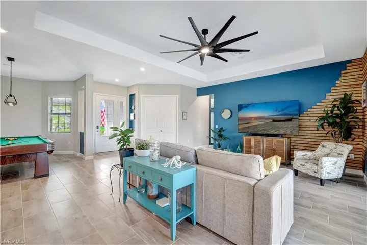 Living area with a raised ceiling, a ceiling fan, baseboards, billiards, and recessed lighting