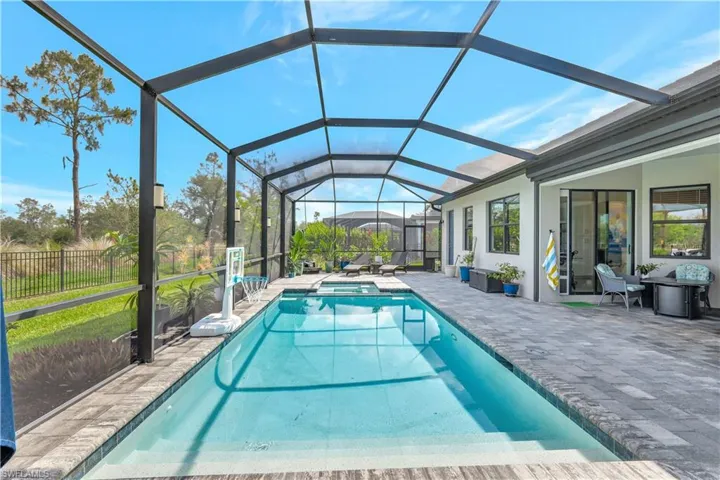 View of pool with a patio area, a pool with connected hot tub, and glass enclosure