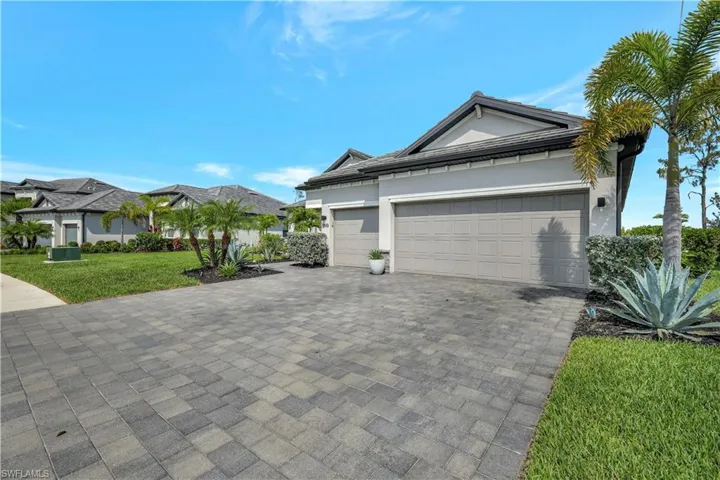View of home's exterior with decorative driveway, a yard, a garage, and stucco siding