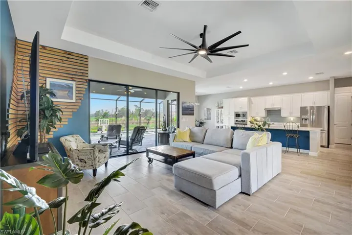 Living room with a tray ceiling, a ceiling fan, and recessed lighting
