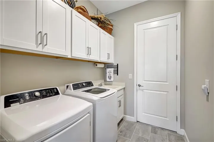 Laundry area with separate washer and dryer, baseboards, and cabinet space