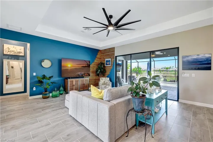 Living area with a ceiling fan, baseboards, and a tray ceiling