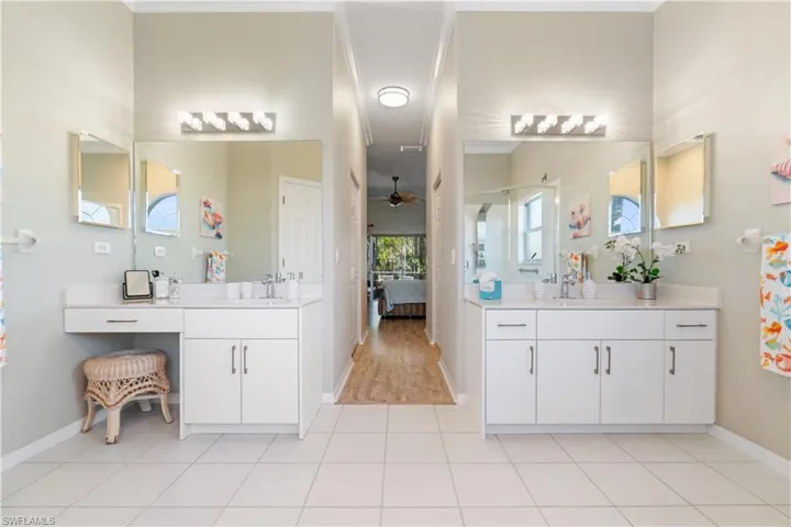 Full bath featuring ceiling fan, two vanities, ensuite bathroom, light tile patterned floors, and crown molding