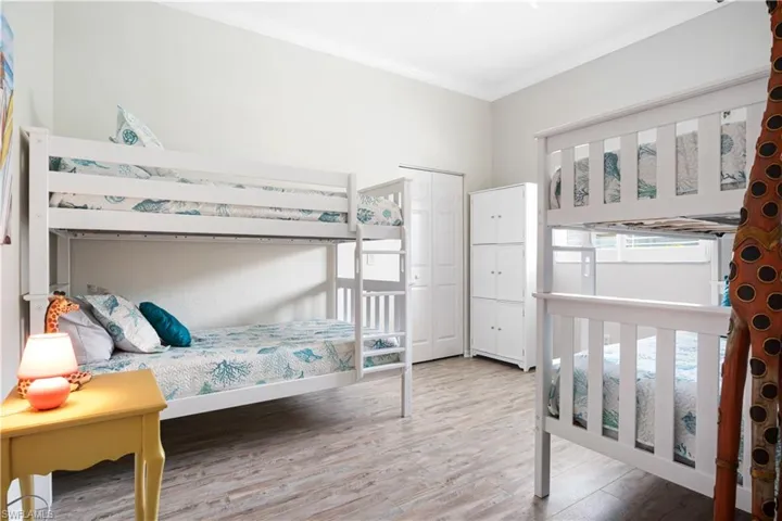 Bedroom featuring light wood-style flooring, crown molding, and a nursery area