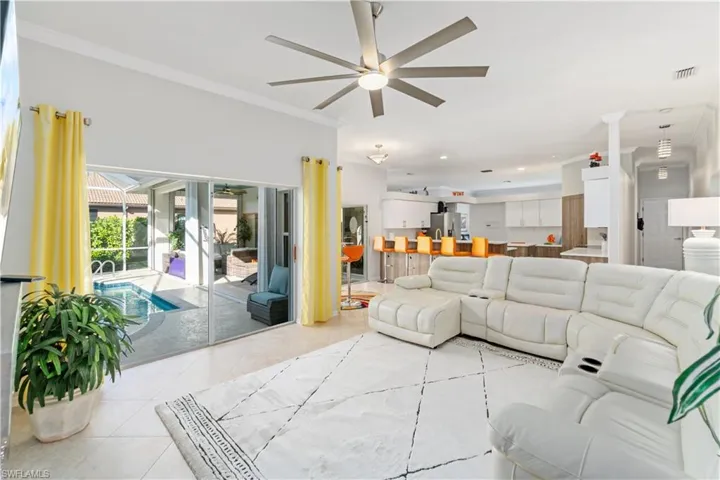 Living room featuring crown molding, a ceiling fan, and light tile patterned floors