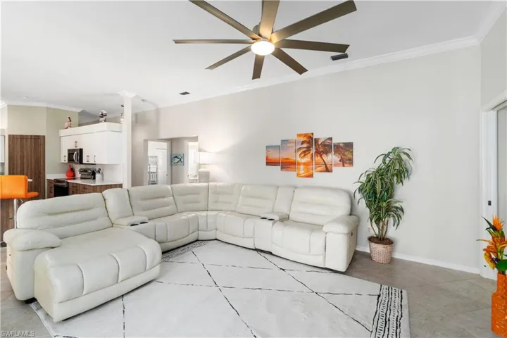 Living area with crown molding, light tile patterned floors, and ceiling fan