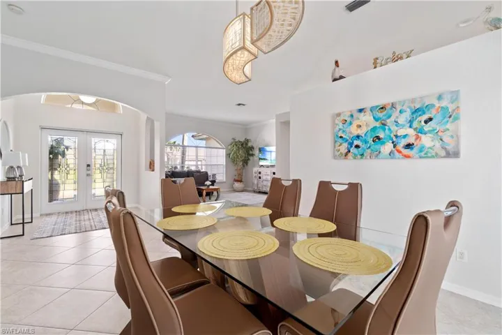Dining space featuring french doors, ornamental molding, light tile patterned flooring, and arched walkways