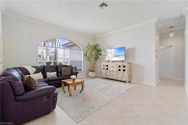 Living room with crown molding and light tile patterned floors