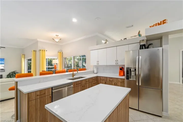 Kitchen featuring light tile patterned floors, stainless steel appliances, open floor plan, ornamental molding, and a peninsula