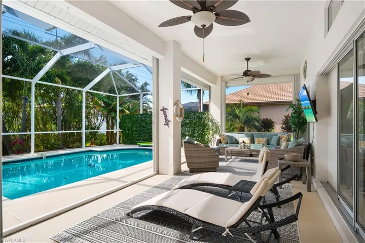 Swimming pool with a patio, glass enclosure, outdoor lounge area, and a sunroom