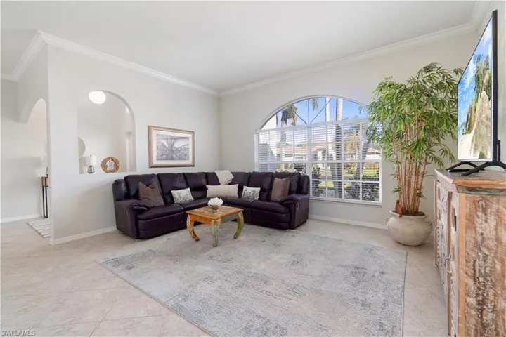 Living area featuring ornamental molding, light tile patterned floors, and arched walkways