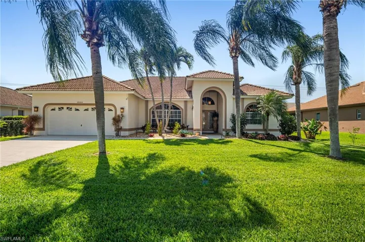 Mediterranean / spanish-style house featuring an attached garage, stucco siding, a front lawn, and driveway