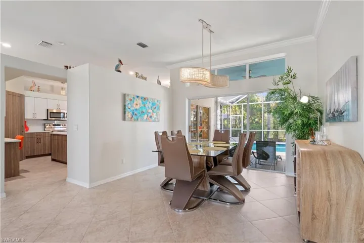 Dining room with a sunroom, light tile patterned floors, and crown molding