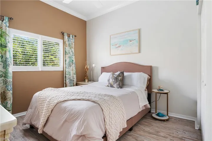 Bedroom with crown molding, wood finished floors, and a ceiling fan