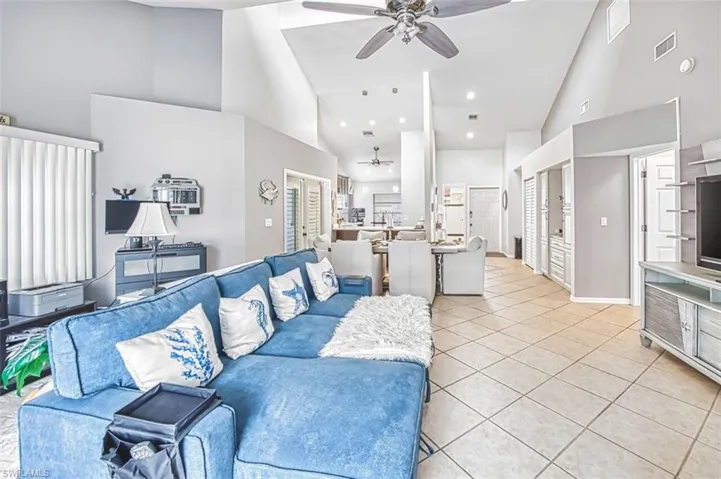 Living room featuring a ceiling fan, lofted ceiling, light tile patterned flooring, and recessed lighting