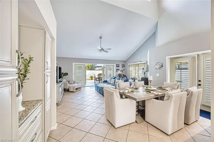 Dining area with french doors, a ceiling fan, light tile patterned floors, and vaulted ceiling