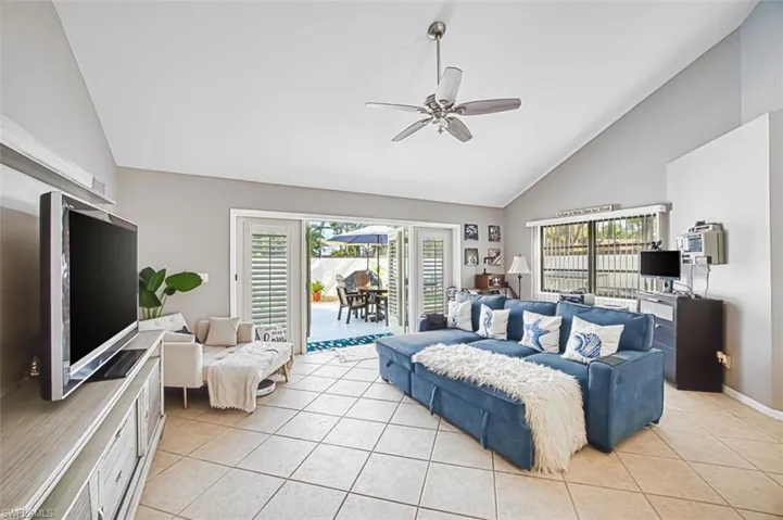 Living area with vaulted ceiling, ceiling fan, and light tile patterned floors
