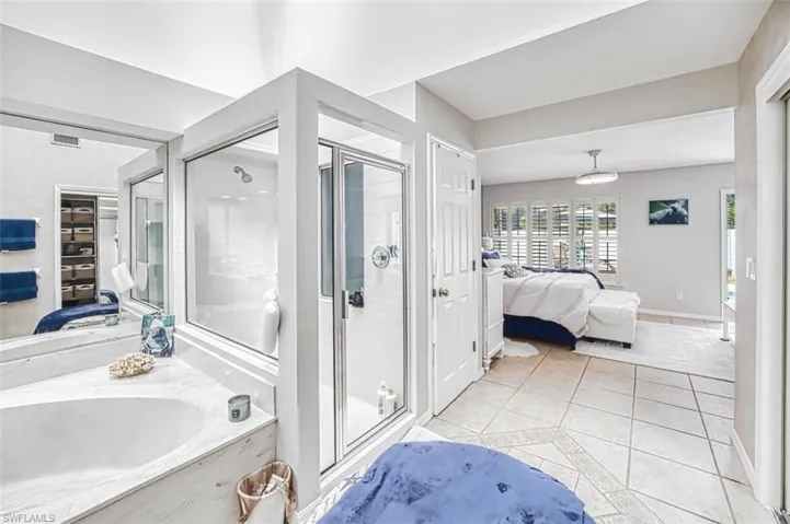 Ensuite bathroom featuring a stall shower, light tile patterned flooring, and a garden tub