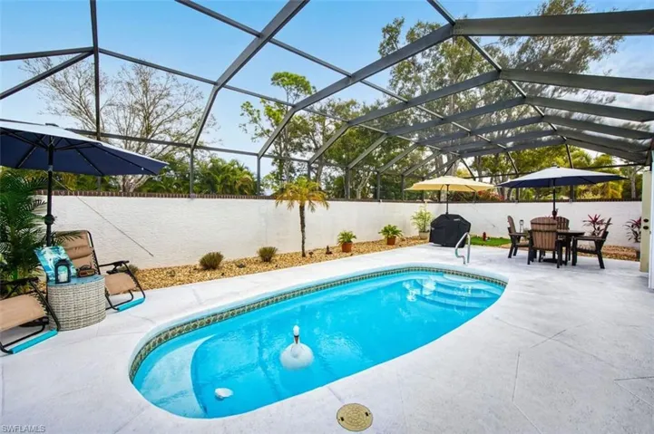View of pool with a fenced backyard, glass enclosure, a sunroom, outdoor dining area, and patio surround