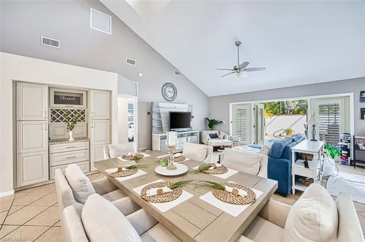 Dining space with vaulted ceiling, healthy amount of natural light, light tile patterned flooring, and ceiling fan