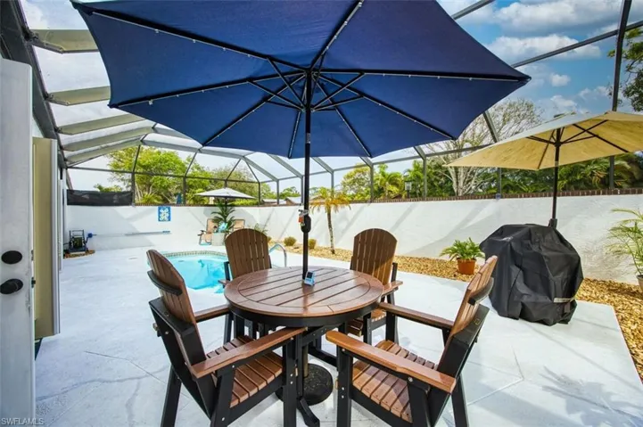 Fenced backyard with glass enclosure, a sunroom, grilling area, outdoor dining area, and a patio