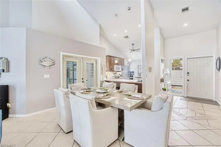 Dining space with french doors, vaulted ceiling, ceiling fan, light tile patterned floors, and recessed lighting
