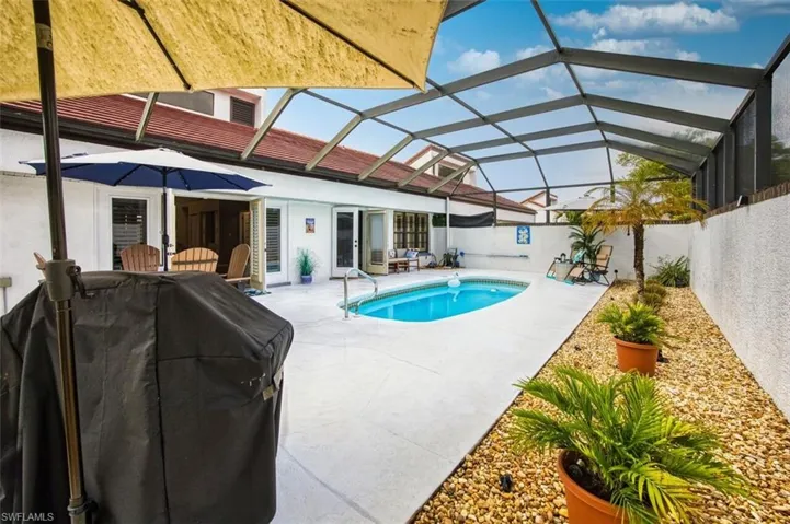 Swimming pool featuring a sunroom, a lanai, a patio area, and area for grilling