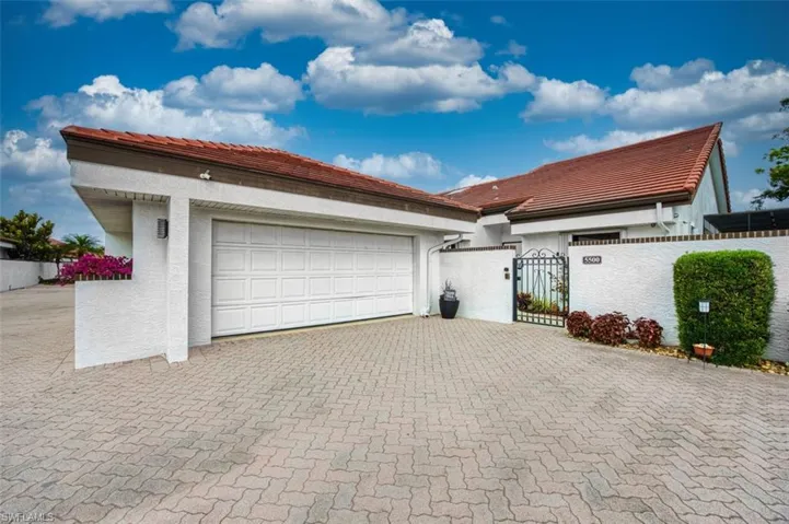 View of front facade with a gate, stucco siding, a garage, and decorative driveway