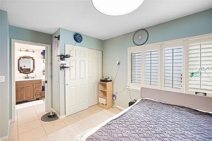 Bedroom with a closet, light tile patterned floors, and ensuite bath
