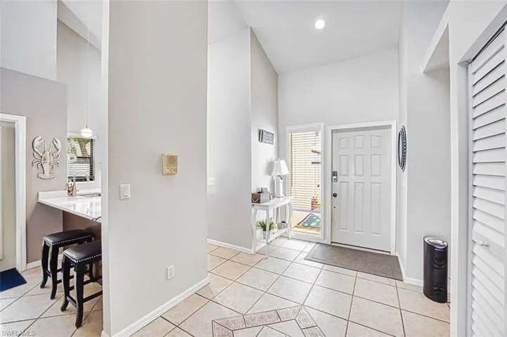 Entryway featuring light tile patterned flooring and vaulted ceiling