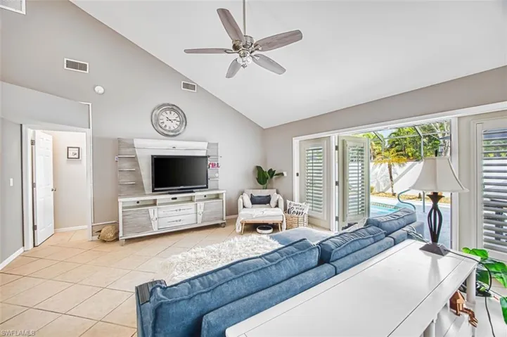 Living area featuring a ceiling fan, lofted ceiling, and light tile patterned floors