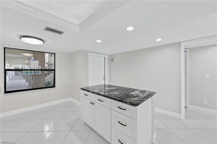 Kitchen with white cabinetry, dark stone countertops, a center island, recessed lighting, and light tile patterned floors