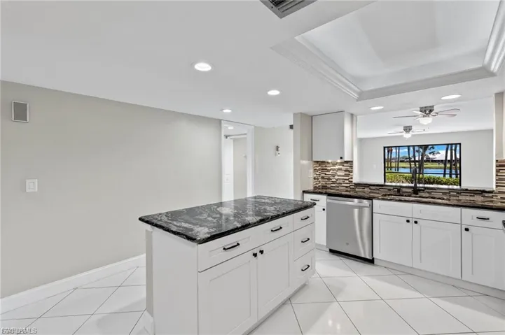 Kitchen with dark stone countertops, white cabinetry, dishwasher, recessed lighting, and tasteful backsplash