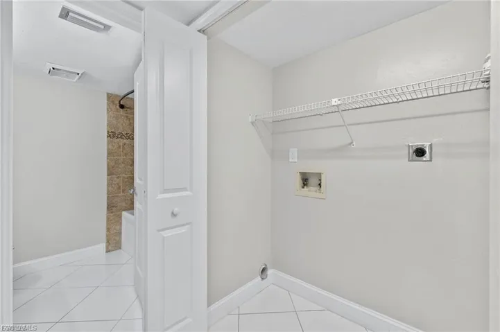 Washroom with hookup for an electric dryer, light tile patterned floors, and washer hookup