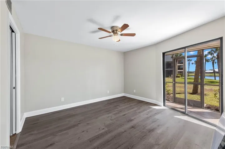 Unfurnished bedroom featuring access to exterior, dark wood finished floors, ceiling fan, a water view, and a closet