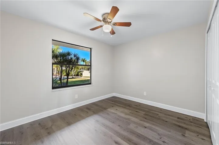 Empty room with dark wood-style flooring and ceiling fan
