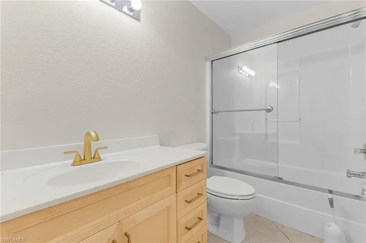 Full guest bathroom featuring vanity, tile patterned floors, enclosed tub / shower combo, and toilet