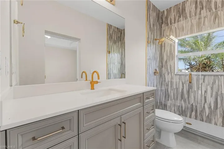 Cabana bathroom featuring vanity, tiled shower, tile patterned floors, and toilet