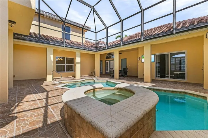 Courtyard area with view of heated pool featuring a spillover spa, a lanai, ceiling fan, and a patio