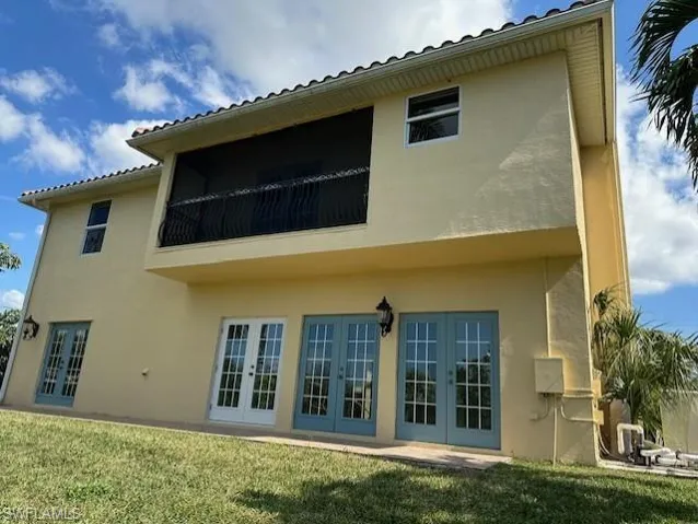 Back of property featuring a lawn, french doors, and a balcony