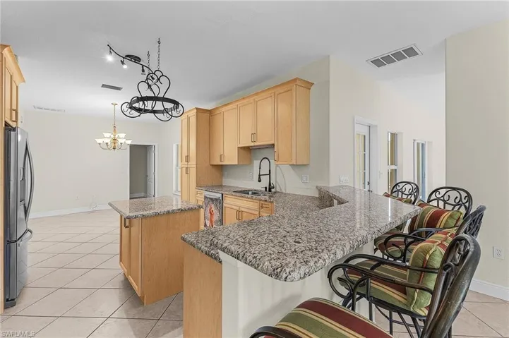 Eat-in kitchen with sink, a breakfast bar area, decorative light fixtures, a kitchen island, and stainless steel appliances