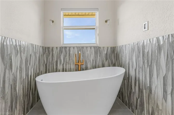 Master bathroom featuring tile patterned floors, tile walls, and a washtub